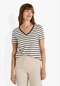Camiseta de rayas con escote en V en crema y azul marino. Manga corta, con un pequeño detalle bordado en el lado izquierdo del pecho. Material de algodón suave.