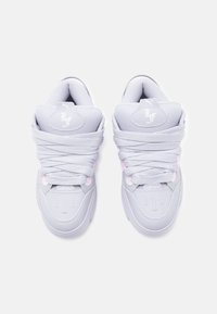 Pár bílých tenisek Puma LaFrancé s tlustými tkaničkami, logem ve gotickém stylu na špičkách a polstrovanými límci, pohled shora na bílém pozadí.