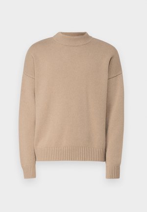 Maglione beige lavorato a maglia con collo alto, bordo e polsini a coste. Presenta una vestibilità rilassata e una texture liscia.