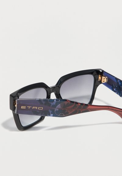 Lunettes de soleil carrées noires avec verres gris dégradés et branches bleues et rouges à motifs, portant l'inscription "ETRO" en lettres dorées.