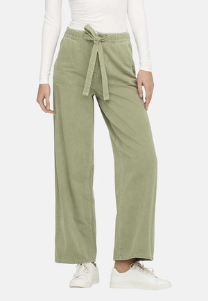 Pantalons larges vert clair en coton doux, avec une ceinture à nouer et une coupe décontractée, associés à des baskets blanches.