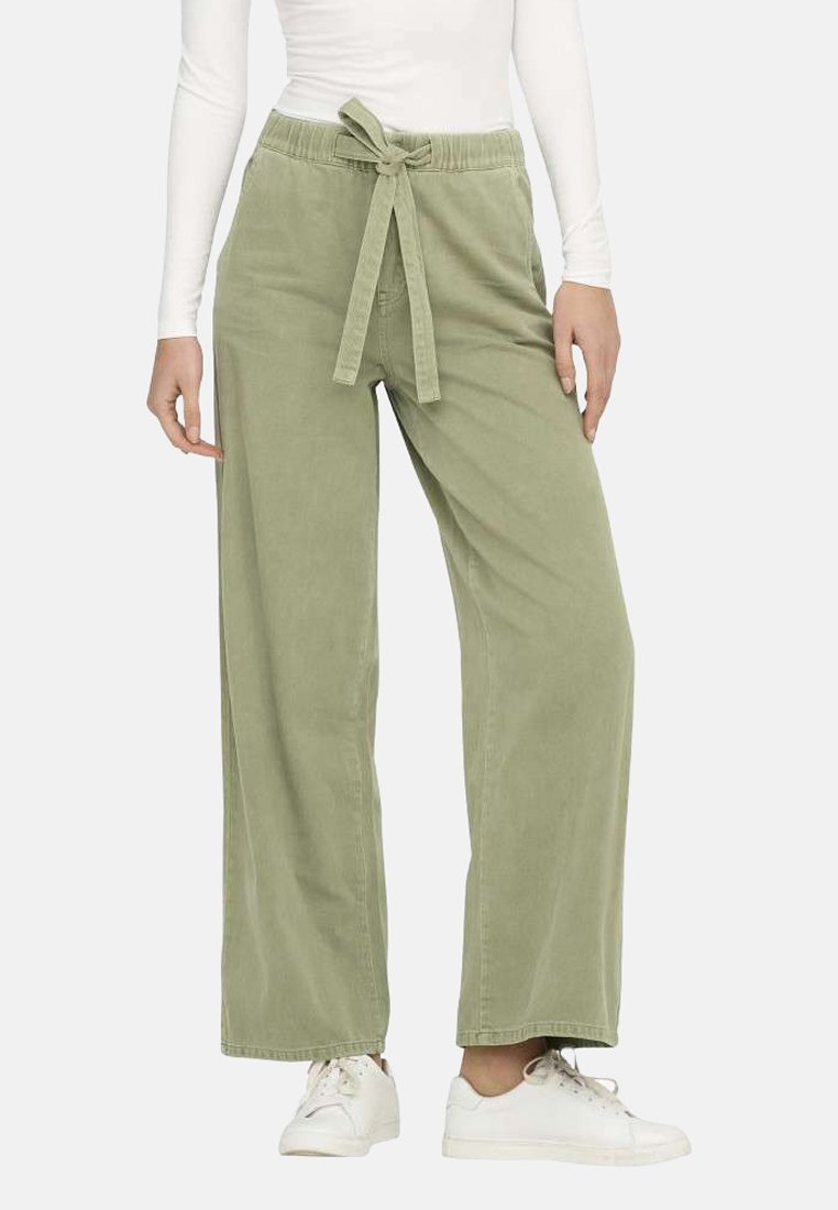 Pantalons larges vert clair en coton doux, avec une ceinture à nouer et une coupe décontractée, associés à des baskets blanches.