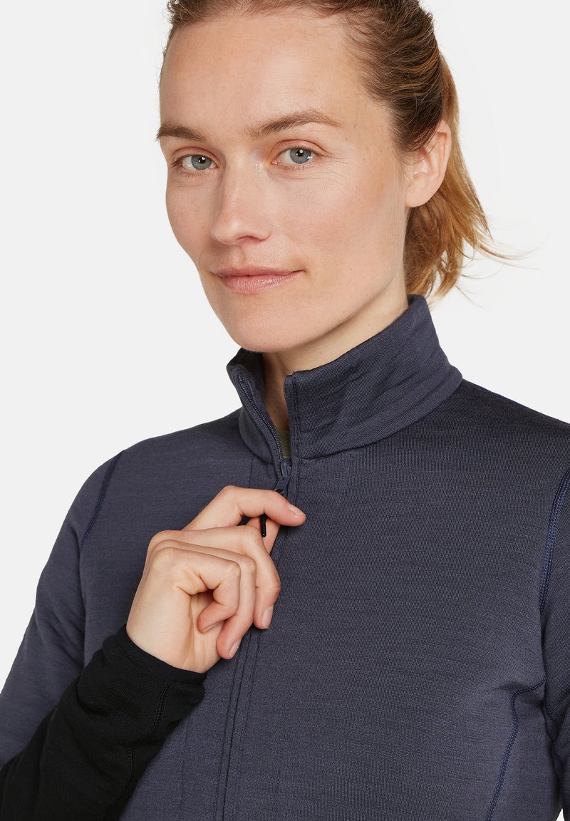 Marinefarbener Reißverschluss-Jacke mit hohem Kragen, strukturiertem Stoff und tailliertem Design. Mit einem kontrastierenden schwarzen Langarmunterlayer und Reißverschluss-Ziehgriff.