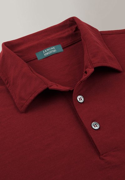 Polo shirt bordeaux realizzato in Ice Cotton; presenta un colletto classico, tre bottoni e un tessuto liscio e testurizzato. Etichetta visibile all'interno del colletto.