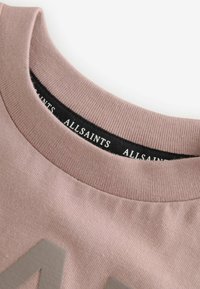 Lys rosa bomuld crew neck t-shirt med tekstureret stof, der har en sort label med "ALLSAINTS" tekst nær halsudskæringen.