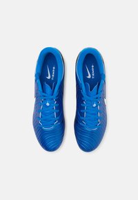 Blue athletic shoes with textured material, contrasting white Nike logo, and flat shoelaces. Includes rubber sole and padded interior.