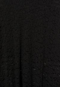 Tessuto nero con una texture che presenta un motivo in rilievo, che ricorda piccoli cerchi e onde. Il materiale appare morbido e leggermente trasparente.