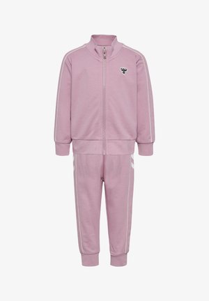 Lichtroze trainingspak met ritsjack en broek. Voorzien van witte gestreepte accenten en een klein logo op de borst. Zachte stoftextuur.