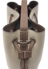 Beżowa skórzana torba w kształcie wiadra z ciemnobrązowym sznurkiem i uchwytem, białym przeszyciem i srebrnymi oczkami, pokazana od góry.