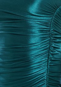 Teal satiinikangas, jossa on rypistetty ja poimuisa tekstuuri, luoden vaakasuoria ja pystysuoria taitteita, jotka muodostavat kiiltävän ja sileän kuvion.