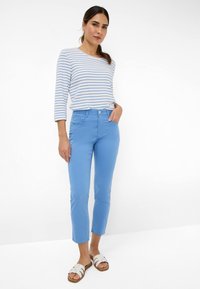 Lichtblauwe cropped broek met een knoopsluiting aan de voorkant, twee zakken aan de voorkant en een gladde textuur, gecombineerd met een gestreept longsleeve shirt.