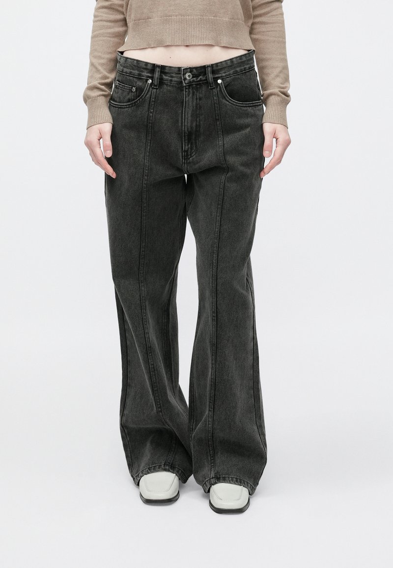 Črne flare kavbojke z visokim pasom, zapenjanjem na gumb in zadrgo, dvema sprednjima žepoma ter izrazitimi šivi.