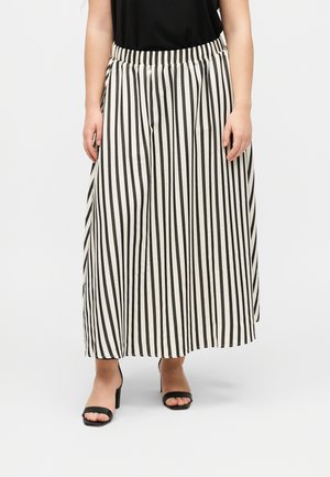 Frau trägt schwarz-weiß gestreifte, weit geschnittene Hosen mit elastischem Bund und schwarzen offenen High-Heel-Sandalen.