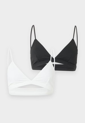 Deux bralettes à bonnets triangulaires avec fines bretelles, une noire et une blanche, avec un détail d'ouverture à l'avant, présentées sur un fond clair.