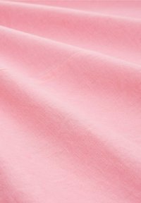 Světlé růžové látky s hladkým, strukturovaným povrchem, který ukazuje jemné záhyby a subtilní variace v barvě a odrazu světla.