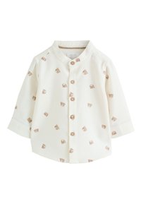 Chemise blanche à boutons avec col mao, ornée d'impressions éparses d'ours brun clair et de manches longues. Fermeture par boutons à l'avant.