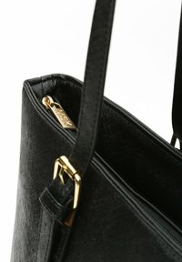 Borsa nera realizzata in materiale testurizzato, dotata di chiusura con zip e dettagli in metallo dorato. Inclusa una tracolla regolabile.