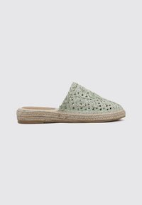 Zueco de esparto verde tejido con punta afilada, suela de yute y parte superior texturizada que presenta un diseño estampado. Estilo plano y casual.