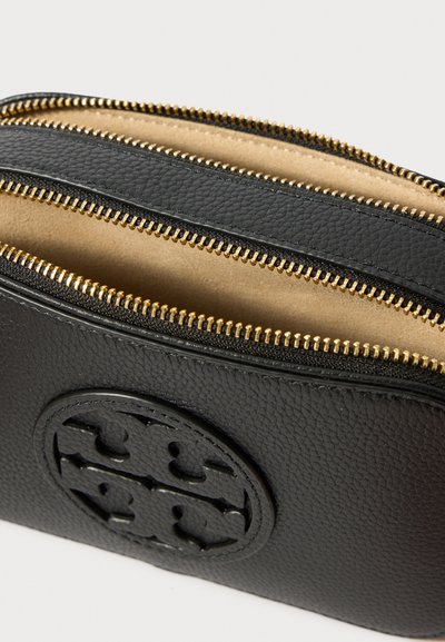 Bolsa de pele texturizada preta com dois fechos de correr dourados abertos e um logo redondo em relevo na frente, mostrando o forro interior em bege.