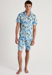 Lichtblauw set met korte mouwen en shorts, voorzien van ingewikkelde zon- en maanpatronen in blauw, geel en donkerblauwe accenten. Soepele stofstructuur.