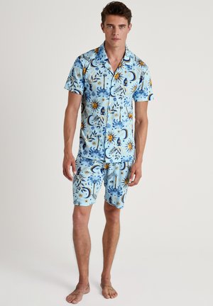 Himmelsblaues Kurzarmhemd und Shorts-Set mit komplexen Sonnen- und Mondmustern in Blau, Gelb und dunkelblauen Akzenten. Glatte Stofftextur.