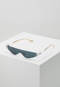 Ochelari de soare cu lentile gri închis, rame din plastic transparent și brațe din metal aurit. Design elegant, tip wraparound, cu detalii accent distinctive.
