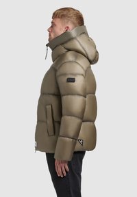Olive green puffer jacket with a hood, featuring a quilted design, side pockets, and a black logo patch on the sleeve. Smooth texture.