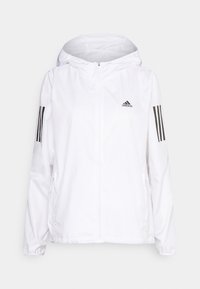 Valkoinen kevyt takki hupulla, jossa on täysipitkä vetoketju ja kaksi sivutaskua. Musta Adidas-logo ja kolme mustaa raitaa hihoissa.