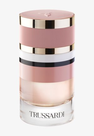 Flacon de parfum en verre transparent avec liquide rose, bouchon côtelé rose et or, et "TRUSSARDI" imprimé en noir à la base.