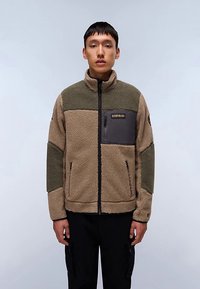 Hellbraune Fleecejacke mit grünen und schwarzen Akzenten, durchgehendem Reißverschluss, hohem Kragen und einer Brusttasche. Texturiertes Material mit gemütlichem Aussehen.