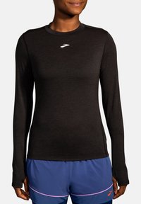 Top atletico a maniche lunghe nero realizzato in tessuto liscio; presenta un collo rotondo e un logo sul petto. Senza motivi o accenti prominenti.