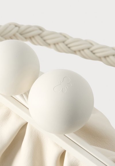 Sac cabas blanc avec une base en tissu texturé. Deux poignées circulaires présentent une finition mate lisse et un logo papillon embossé.