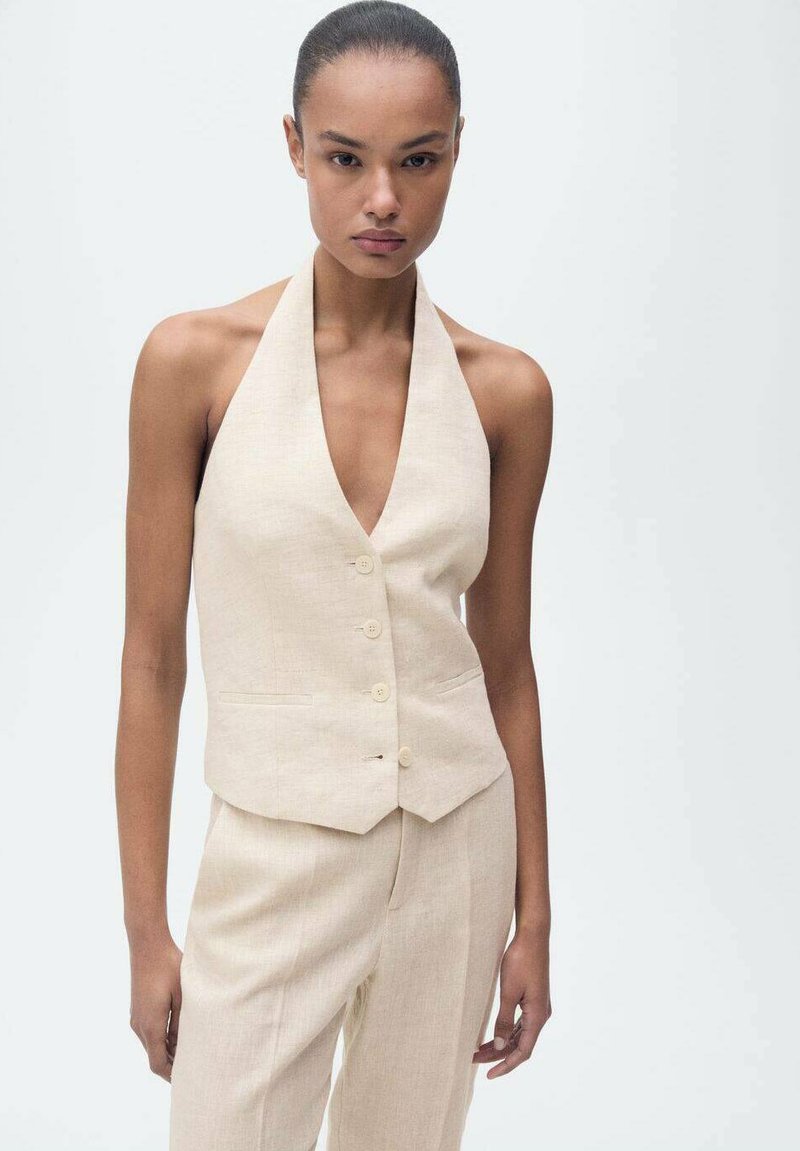 Light beige linen halter neck vest with a fitted design, featuring a deep V neckline, five buttons, and two front pockets.