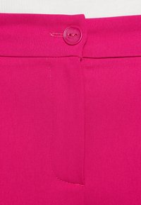 Fuchsia tyg med en platt framsidesdesign, som har en enda rund knapplåsning och ett sidofickdetalj. Slät textur, inga mönster.