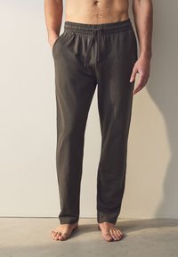 Mørkegrå, lette bomulds-loungebukser med elastik i taljen, snøre og sidelommer. Tætsiddende ved anklerne.