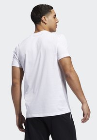 Camiseta de manga corta blanca hecha de mezcla de algodón; cuenta con un cuello redondo y un corte relajado, costuras visibles y una etiqueta en el bajo.
