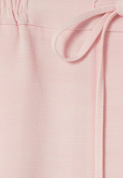 Tissu rose clair avec un cordon noué en un nœud en haut, montrant un matériau tricoté texturé et une taille froncée.