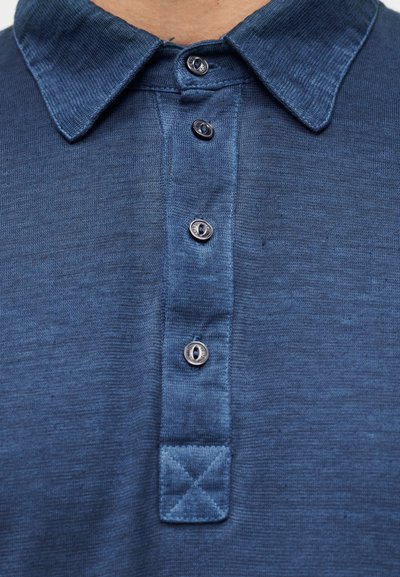 Μπλε σκούρο πόλο μπλουζάκι με υφασμάτινο γιακά, πέντε ασημένια κουμπιά και μια καπιτονέ επιφάνεια κάτω από τον γιακά. Μαλακό ύφασμα με ελαφριά γυαλάδα.