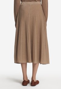 Plisserad midikjol i ljusbrun med subtil lyster. Har ett åtsittande midjeband och når under knäet. Kombineras med bruna ballerinas.