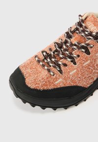 Oranje textuur sneaker met zwarte rubberen zool, met bruine en witte patroonveters en een zacht, pluizig bovenmateriaal.