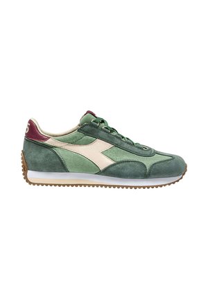 Sneaker verde in suede con accenti color crema, caratterizzati da un design curvo, lacci piatti e una suola in gomma testurizzata. Stile atletico classico.