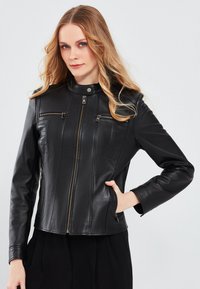 Black leather motorcycle jacket featuring a zip front, two chest pockets with zippers, and a structured fit. Smooth texture and minimal detailing.