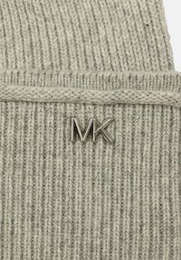 Gorro de punto gris con textura acanalada, que presenta un acento del logotipo plateado de MK en la parte frontal. El material parece suave y cálido.