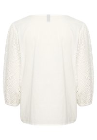 Blusa bianca con maniche puff in tessuto testurizzato e ricamate, caratterizzate da un motivo a zigzag. Corpo liscio con scollatura rotonda e dettaglio con asola sul retro.
