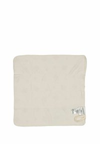 Beige, quiltad tygkvadrat med rundade hörn, etikett på ena sidan och en ögla för upphängning. Mjuk textur, slät yta.