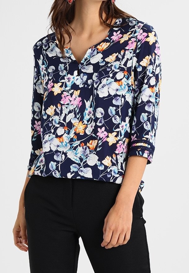 Blusa floreale con sfondo blu navy e fiori vivaci rosa, arancio e blu, scollatura a V e maniche a tre quarti.