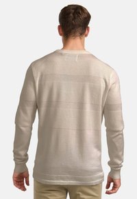 Bézs kötött pulóver texturált mintával, vízszintes csíkokkal. Hosszú ujjakkal és kerek nyakkivágással készült.