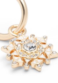 Anhänger in Goldoptik mit Sternform, verziert mit klaren Kristallen und weißen dreieckigen Emailakzenten. Der zentrale Stein ist rund und facettenreich.