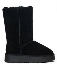 Botín negro de ante con punta redonda, forro aterciopelado y suela gruesa de goma negra. Presenta detalles de costura a lo largo de las costuras.