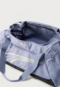 Αθλητική τσάντα duffel ανοιχτού κυρίου διαμερίσματος σε ανοιχτό μωβ χρώμα, με διπλές λαβές, φερμουάρ σε πλαϊνή τσέπη και λογότυπο Puma με καμπύλες κίτρινες ρίγες.